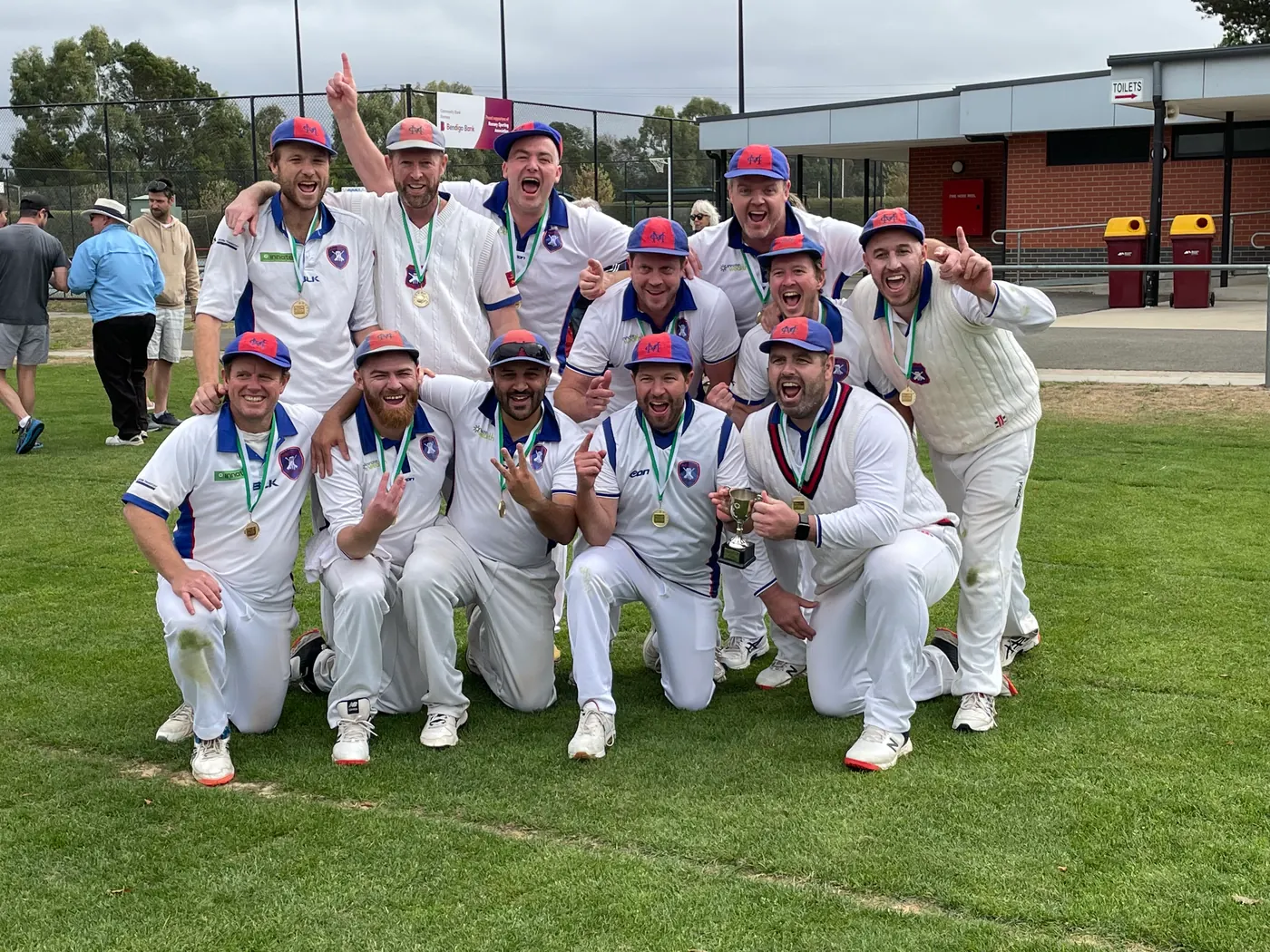 Macedon's senior men celebrating with medals and a trophy